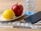 Measuring tape with centimeters and inches, smartphone, pure drinking water, apple and lemon on a brown table. Concept of healthy