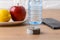 Measuring tape roll, smartphone, bottle of pure drinking water, apple and lemon on a brown table. Concept of healthy eating, diet