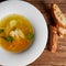 Meat broth with chicken meat, egg and parsley in a white bowl, bouillon with croutons