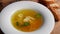 Meat broth with chicken meat, egg and parsley in a white bowl, bouillon with croutons