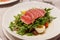 Meat carpaccio with arugula olives and soft-boiled egg. Serving in a restaurant