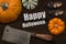 Meat cleaver, pumpkins and girl shoes on wooden background and the message `Happy Halloween`