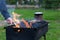 The meat is cooked on the grill, brazier. Close-up man`s hand turns meat on the grate over the fire. Outdoor cooking.