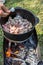 Meat is cooking in the pot on the fire for rice pilau outdoors and man is salting it