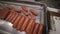 Meat delicacy production. Worker hands operates auotmated production line of sausages and meat products.