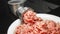 Meat grinder in action and ground beef meat. Horizontal close-up color image of process of grinding preparation of minced raw red