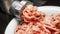 Meat grinder in action and ground beef meat. Horizontal close-up color image of process of grinding preparation of minced raw red