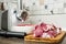 Meat grinder with fresh meat on a cutting board in kitchen interior. Machine for grinding meat into minced meat