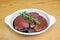Meat marinating: Beef steak eye fillet in white dish of soy sauce marinade and rosemary herb sprig on wooden background with copy