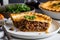 meat pie sitting on white plate, with a slice taken out for easy eating