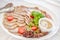 Meat plate with delicious pieces of sliced ham, sausage, meat, tomatoes, horseradish, parskey with herbs and spoon. Close up with