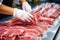 Meat processing plant. A worker sorts cold cuts on a conveyor belt. Arrival of jamon or cold cuts. Production of pork or beef in a