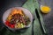 Meat salad with Beef Tenderloin, vegetables, orange, sesame seeds and herbs on a plate close-up. Spoon and fork on a green