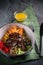 Meat salad with Beef Tenderloin, vegetables, orange, sesame seeds and herbs on a plate top view. Spoon and fork on a green