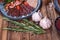 Meat and sausage cuts, garlic, chili peppers, tomatoes and other spices on a wooden brown background