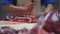 In the meat shop, a worker cuts a piece of meat from a bone