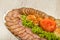 Meat sliced on a mirror dish decorated with verdure.