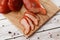 Meat smoked jerky - raw meat sausage meat. Close up view on tasty sliced Chicken basturma on parchment on a wooden board