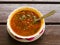 Meat Solyanka, Russian traditional soup with hot spices in a bowl with spoon on wooden table