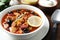 Meat solyanka soup with sausages, olives and vegetables served on table, closeup