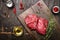 Meat steaks on rustic cutting board with thyme, oil and spices. Dark wooden background