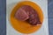 Meat studio image. Piece of fresh meat on an orange plate. Raw meat, beef.