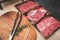 Meat tongs on a cutting board with Sliced fresh meat for steaks or barbecue grilled party at home.