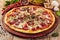 Meat and vegetable pizza on wooden table close up