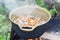 Meat with vegetables is cooked in a cauldron on a fire. Focus on meat