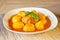 Meatball and potatoes in tomato sauce decorated with basil leaf
