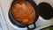 Meatballs in boiling sauce stand on the stove, the man covers the pan with a lid.