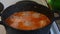 Meatballs in boiling sauce stand on the stove, in a pan with the lid removed.