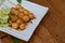 Meatballs toasted on wood dish and a sauce decorated with coriander placed on the table brown wood. Grill pork balls pour at