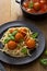 Meatballs with tomato sauce and spaghetti, pasta in black mate plate on wooden background, delicious mediteranean food