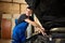 Mechanic in a blue suit is repairing a black car