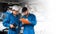 Mechanic in blue workwear uniform checks the vehicle maintenance checklist with his assistant under the lifted car.