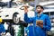 Mechanic in blue workwear uniform holding tablet and check something with blur lifted car in the background. Automobile repairing