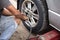 Mechanic changing car wheel with ipneumatic wrench changing car