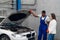 Mechanic and client inspect engine of car