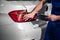 Mechanic with clipboard inspects a car bumper