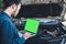 Mechanic Engineer is Diagnosing Car Engine and Electric Adjusting Transmission With Computer Laptop, Automobile Service Man