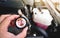 A mechanic hand is clutching a radiator cap with a high temperature dangerous warning notice