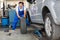 Mechanic hands in blue uniform pushing a black tyre