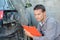 Mechanic holding clipboard assessing car