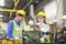 Mechanic holding a wrench and a tablet standing in front of an machine. Engineers and skilled technicians are looking forward