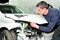 Mechanic inspecting car body damage at auto repair shop service