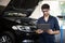 Mechanic inspects the car undercarriage way and makes a note on his inspection sheet. Automobile service, car mechanic