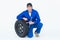 Mechanic leaning on tire while holding wheel wrenches