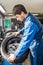 Mechanic Mounting Car Tire On Alloy Rim In Garage