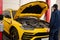 Mechanic open hood of yellow sport car suv